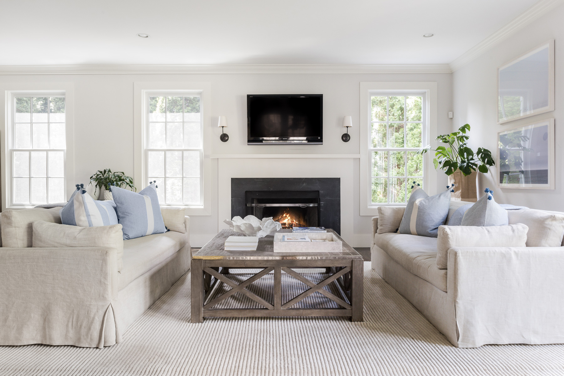 Living room with linen sofas facing a lit fireplace